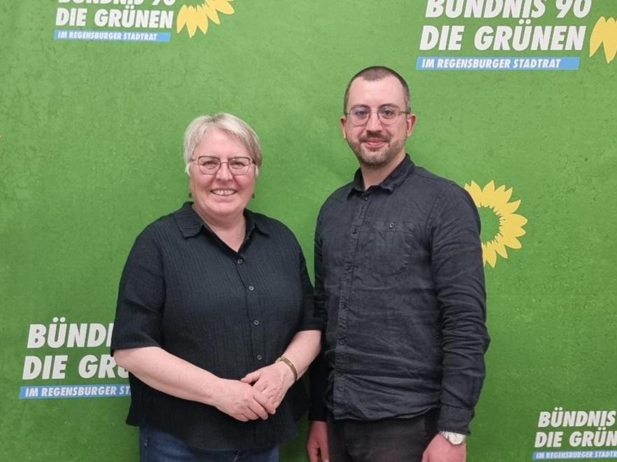 Die wiedergewählten Fraktionsvorsitzenden Maria Simon und Daniel Gaittet stehen vor grünem Hintergrund mit dem Logo von Bündnis 90/Die Grünen.